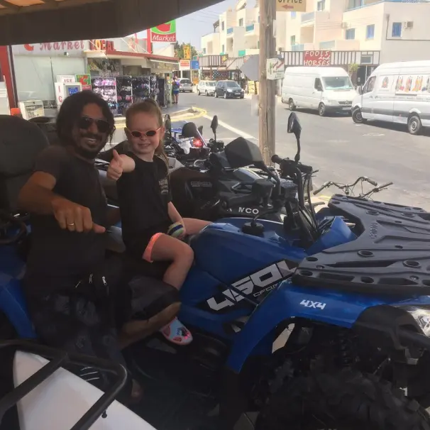 A dad and his daughter riding an ATV for rent.
